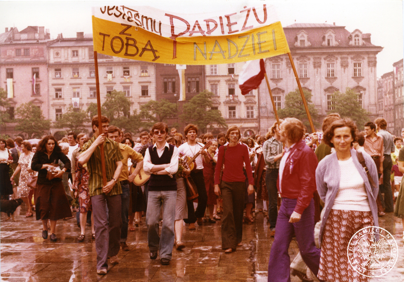 Wierni na Rynku Głównym przed kościołem Mariackim. Mężczyźni niosą transparent z napisem: "Jesteśmy z Tobą Papieżu Nadziei". 9 VI 1979 r. Sygnatura: IPNKr-7-7-1-62