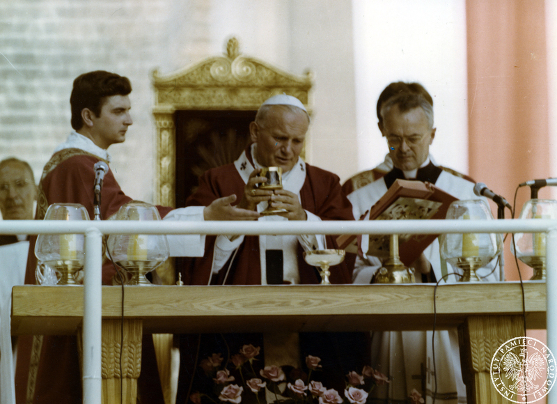 Jan Paweł II w czasie koncelebracji mszy świętej za ołtarzem polowym na Wzgórzu Lecha. Pierwszy z prawej ceremoniarz papieski ksiądz Virgilio Noe. 3 VI 1979 r. Sygnatura: IPNPO-7-7-1-12