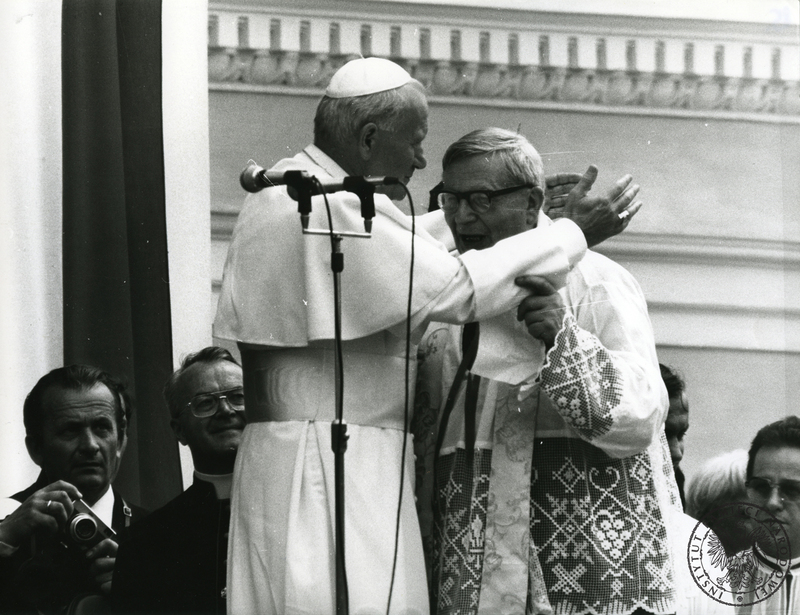 Jan Paweł II obejmuje  księdza Edwarda Zachera swojego byłego katechetę, w czasie spotkania z wiernymi na wadowickim rynku. Z lewej ceremoniarz papieski ksiądz Virgilio Noe. Sygnatura: IPNPo-7-7-1-84